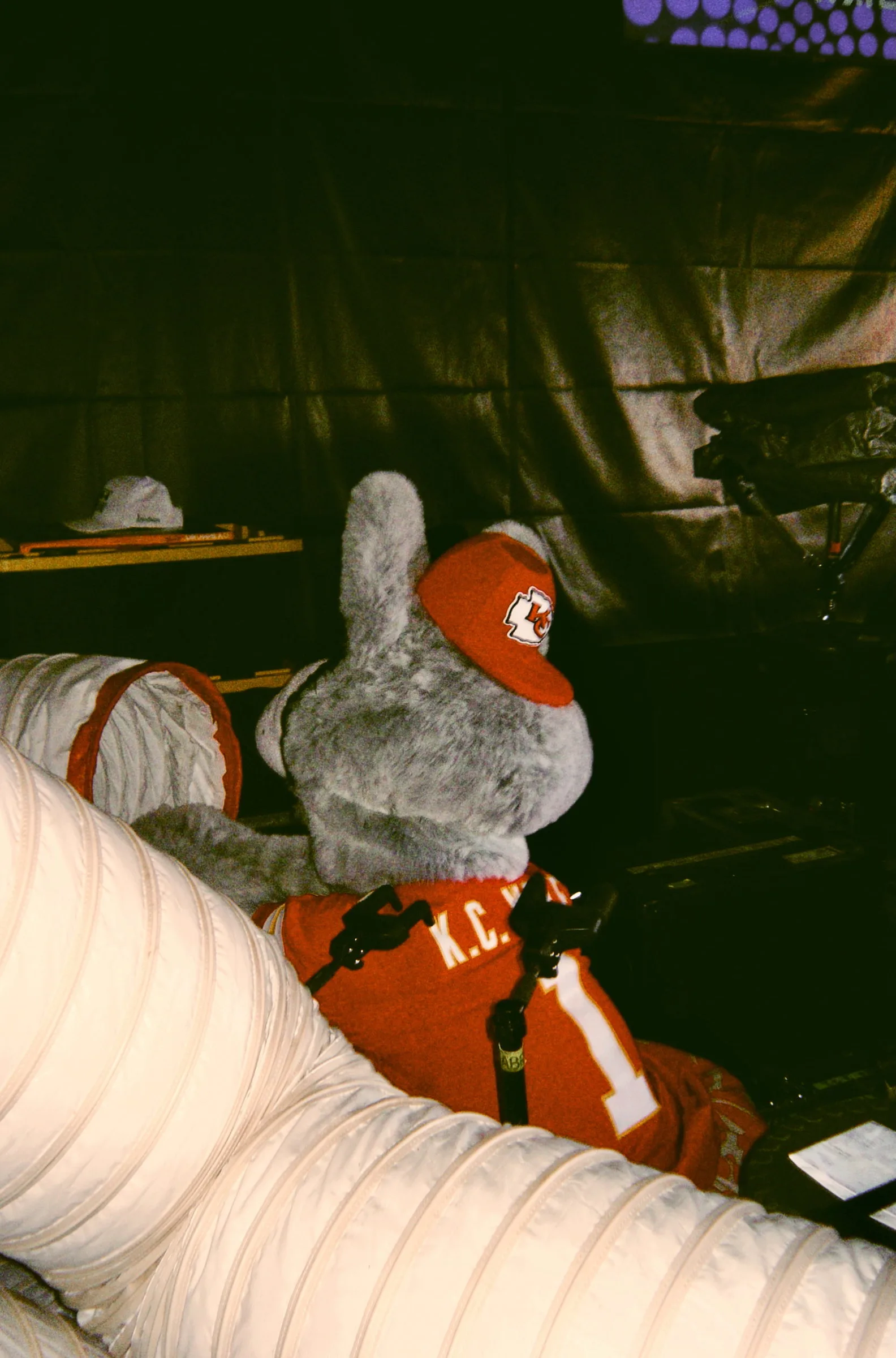 The mascot resting on coils of white ducting backstage, off duty