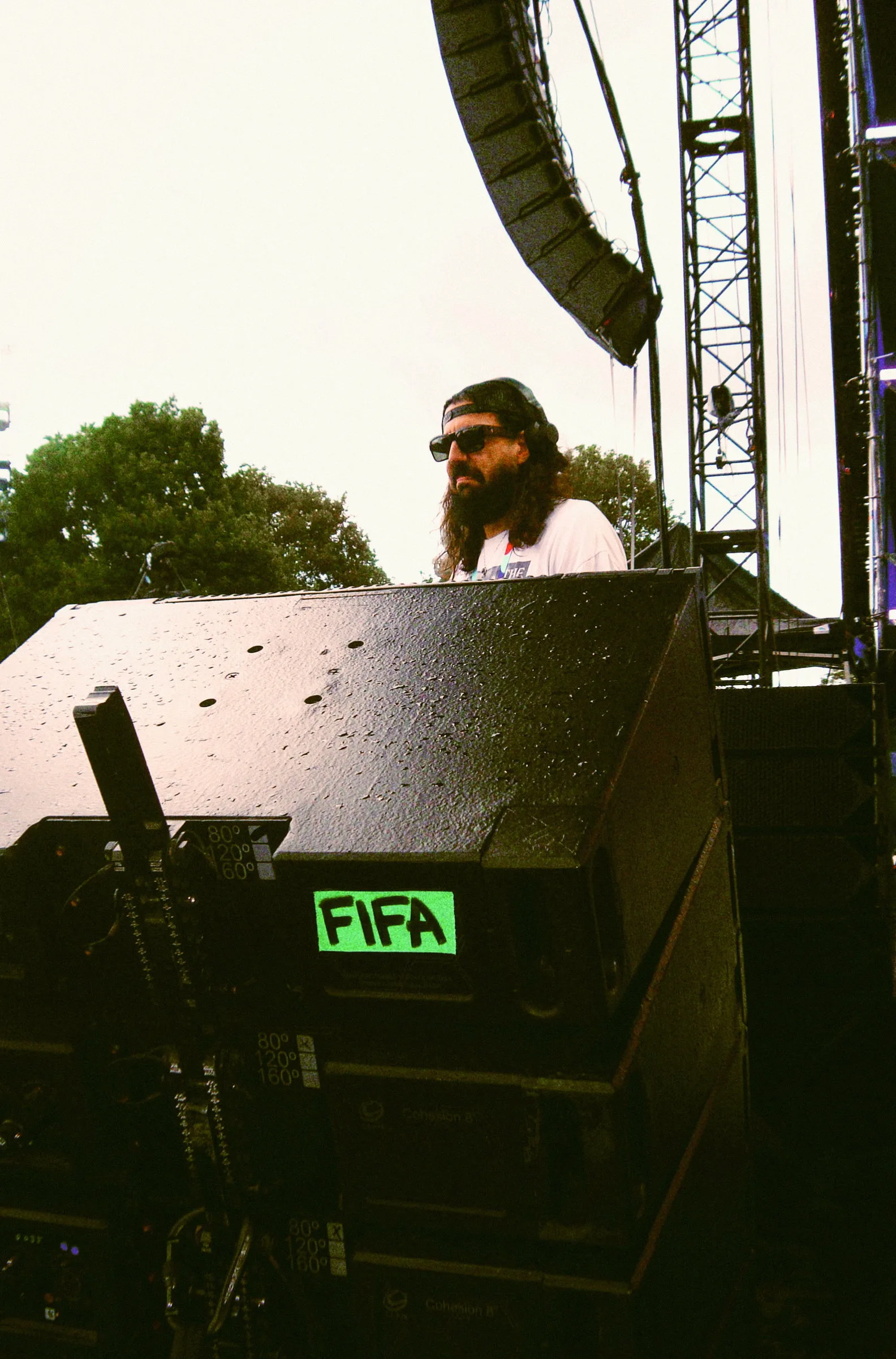 A DJ behind a stage monitor with a strip of green tape marked FIFA stuck to it